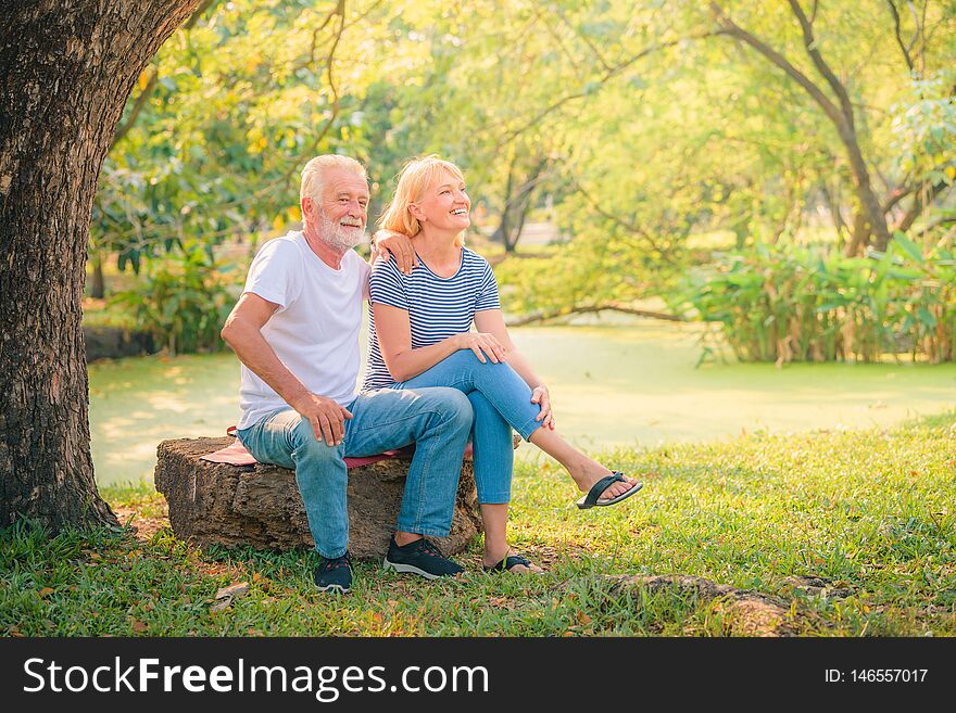 Elderly couple reading newspaper in garden at sunset. Concept couple elder love