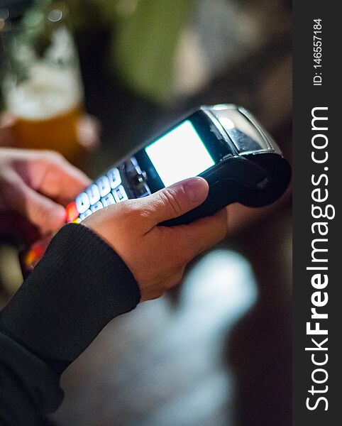 Cropped view of womens hand using credit card to make payment on Payment terminal in bar