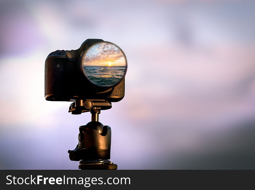 A sunset is reflected in the lens of a professional slr camera. A sunset is reflected in the lens of a professional slr camera