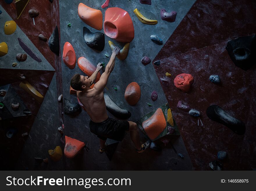 Athletic man practising in a bouldering gym.