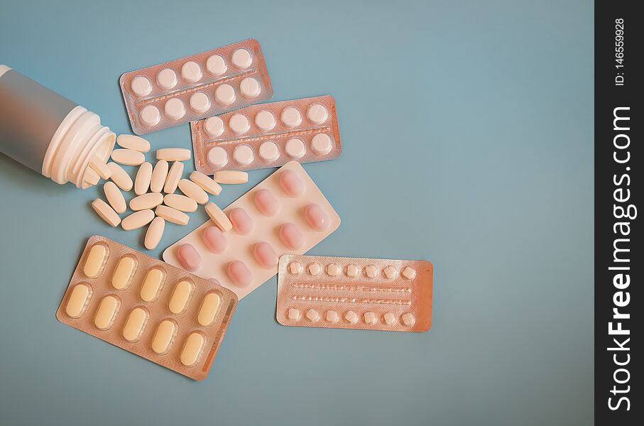 Bottle with pills and blisters with pills and capsules on blue background. Top view, copy space