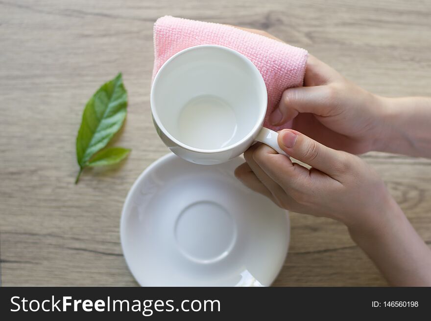 Close up woman hand cleaning coffee cup on the morning with microfiber cloth,Close up woman hand cleaning coffee cup on the rustic wood table.