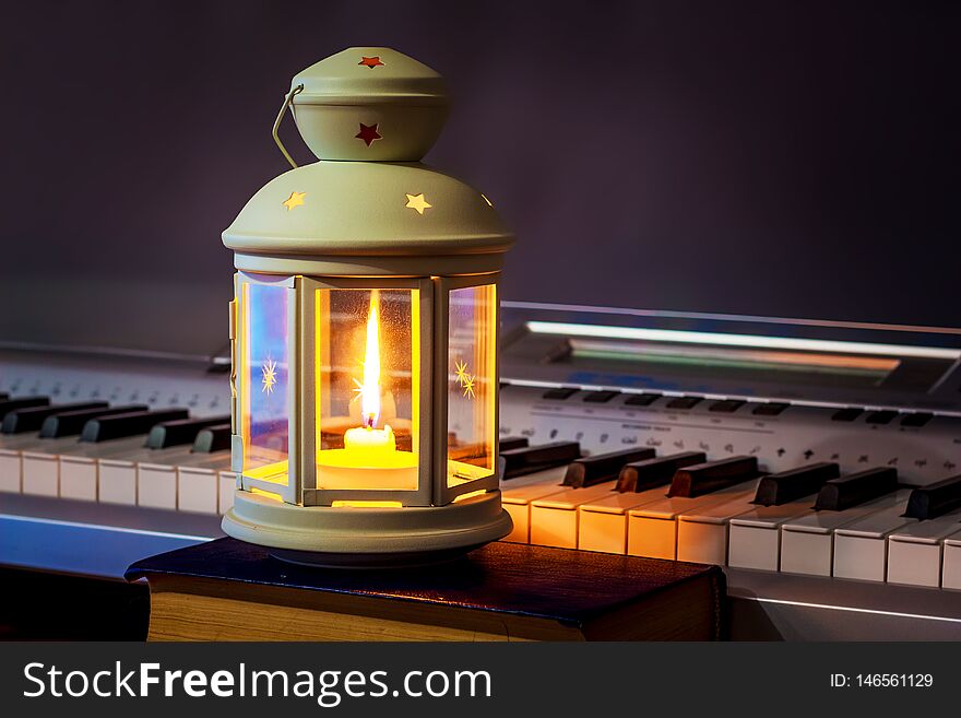 The Lantern With A Candle Illuminates The Keys To The Piano. Music In An Intimate Setting_