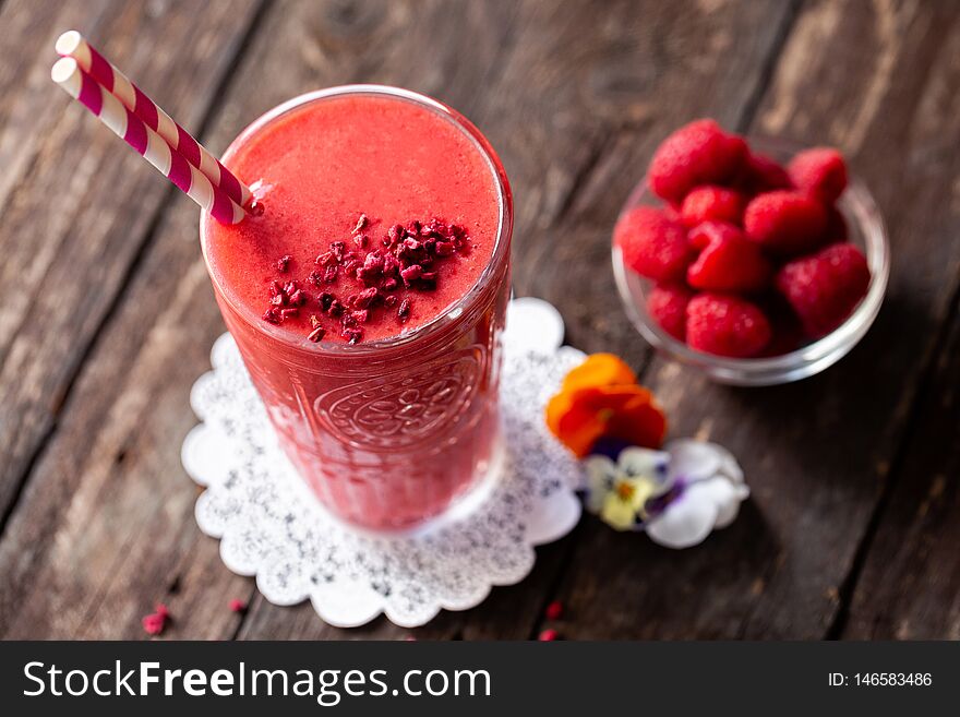 Delicious smoothie made of berries served on the table in glass with two straws in purple-red and white color combination, refreshing food-beverage