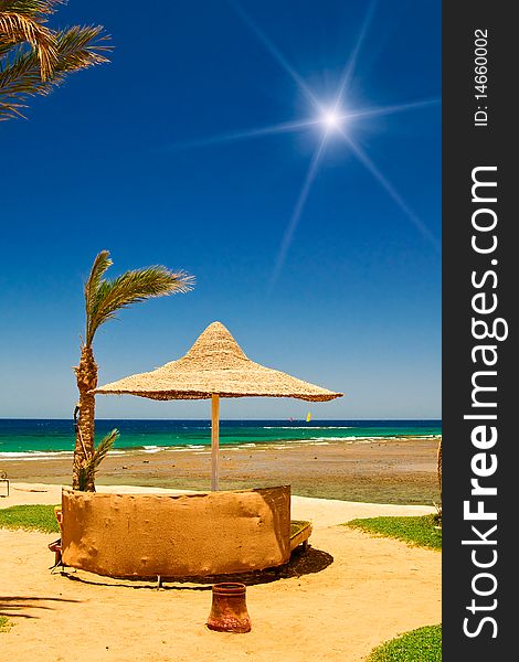 Palm, Parasol And Sea Against Blue Sky.