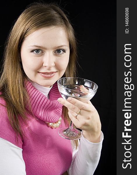 The young woman drinks water from a glass the black background. The young woman drinks water from a glass the black background