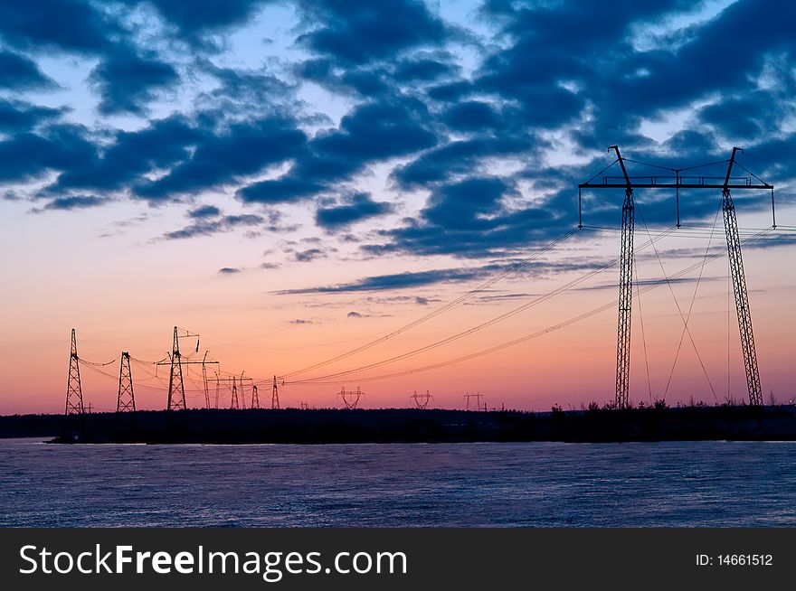 Electric pylons silhouettes against a background of purple sunset sky. Electric pylons silhouettes against a background of purple sunset sky