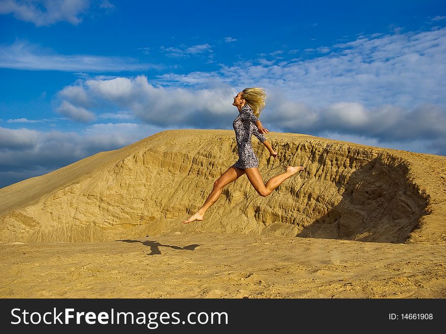 Young beautiful woman is having fun while sun is shinging and she jumping in the sand. Young beautiful woman is having fun while sun is shinging and she jumping in the sand.