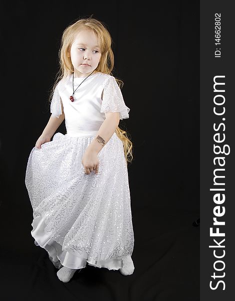 The girl the princess in a white dress standing opposite to a black background. The girl the princess in a white dress standing opposite to a black background