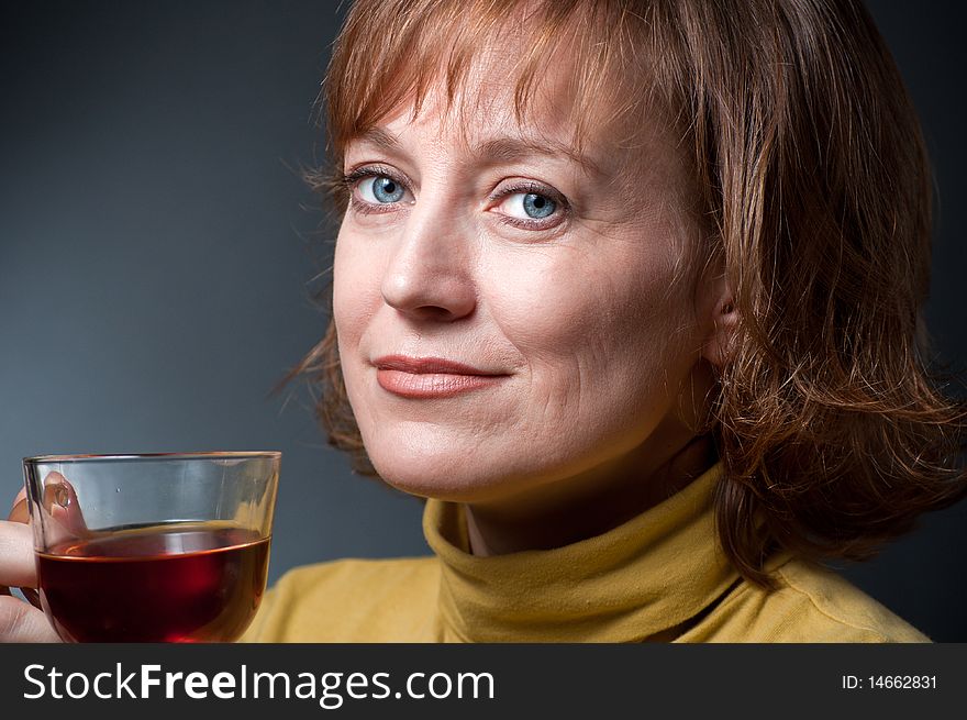 Portrait of a blue-eyed woman in a pale green sweater with a cup tea. Portrait of a blue-eyed woman in a pale green sweater with a cup tea