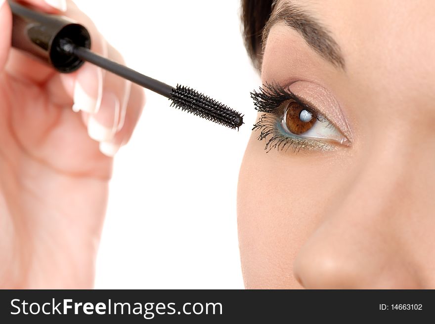Young brown eyed lady applying mascara using lash brush
