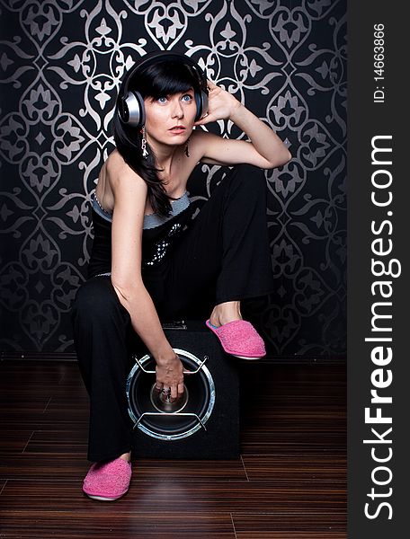 Cool girl sitting on a subwoofer with headphones on. Cool girl sitting on a subwoofer with headphones on