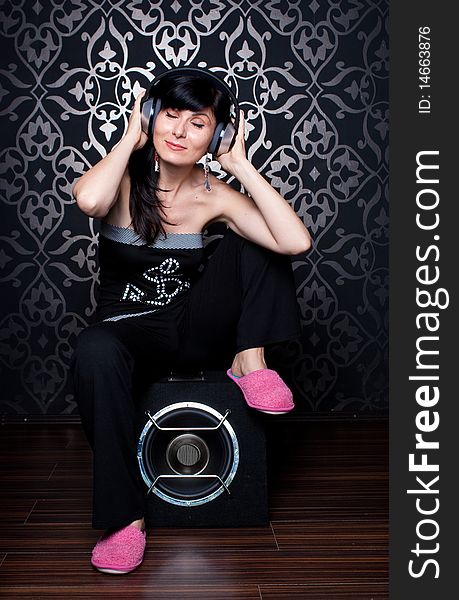 Cool girl sitting on a subwoofer with headphones on. Cool girl sitting on a subwoofer with headphones on