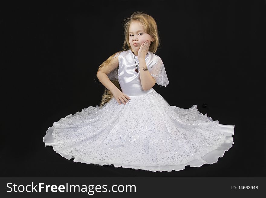 The girl the princess in a white dress sits opposite to a black background. The girl the princess in a white dress sits opposite to a black background