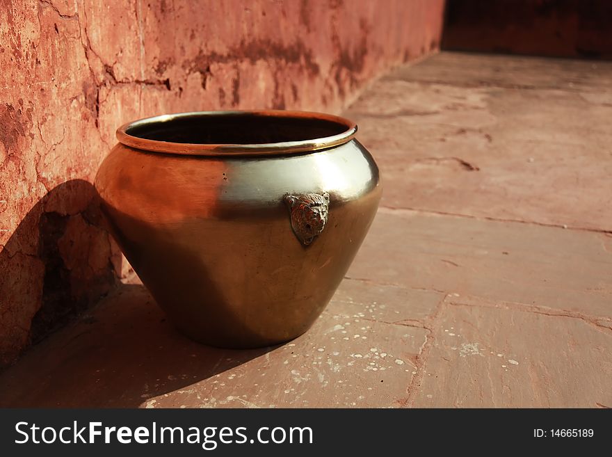 Vintage East Indian brass pot in a stone courtyard.