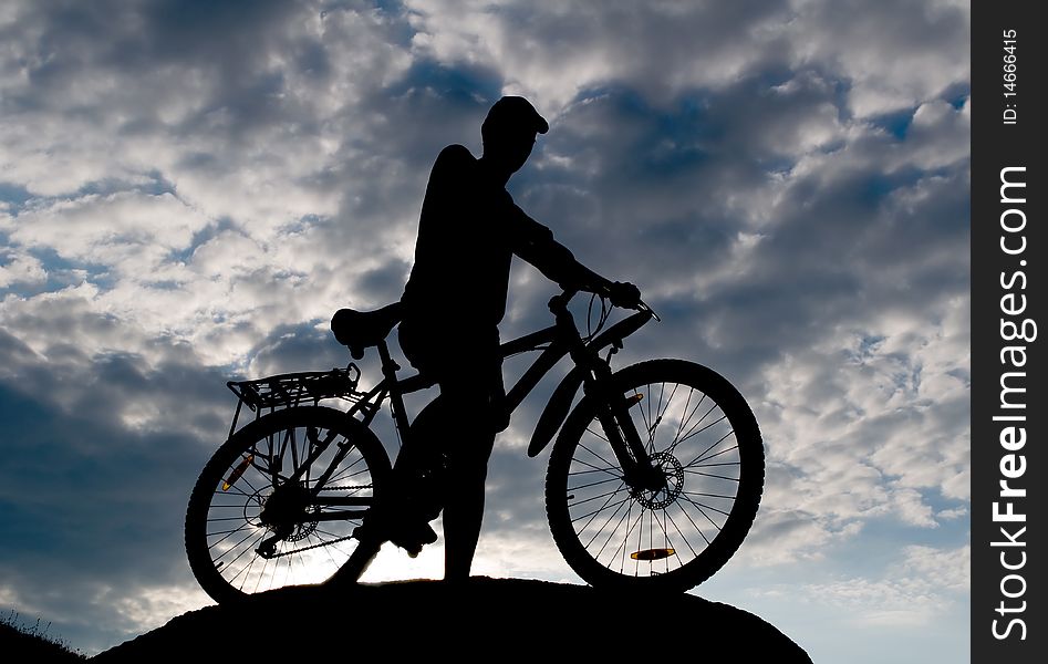 Biker silhouette opposite cloudy sky