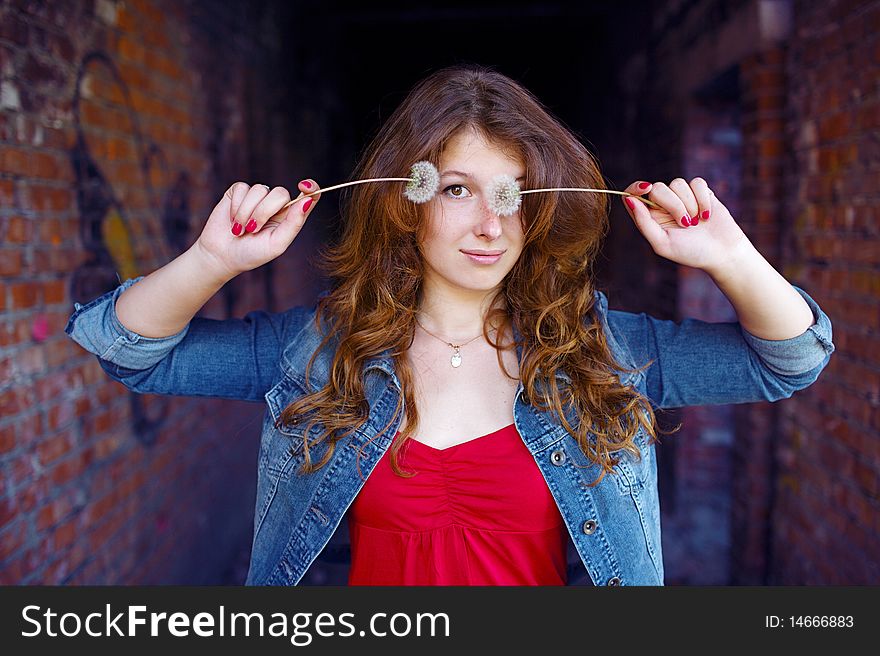 Girl closing one eye with dandelion. Girl closing one eye with dandelion