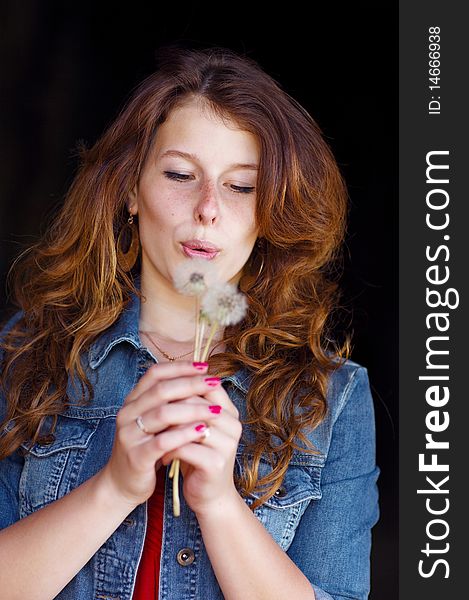 Young girl blowing on two dandelions