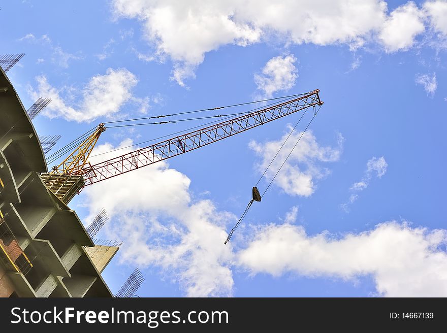 Building with elevating crane and clouds on background