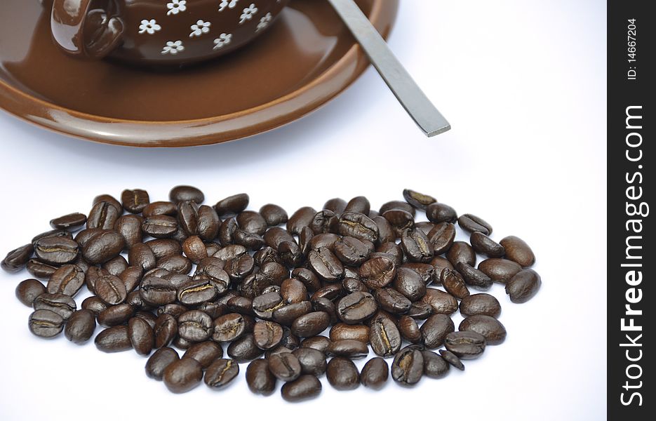 Coffee beans in foreground with cup and saucer. Coffee beans in foreground with cup and saucer