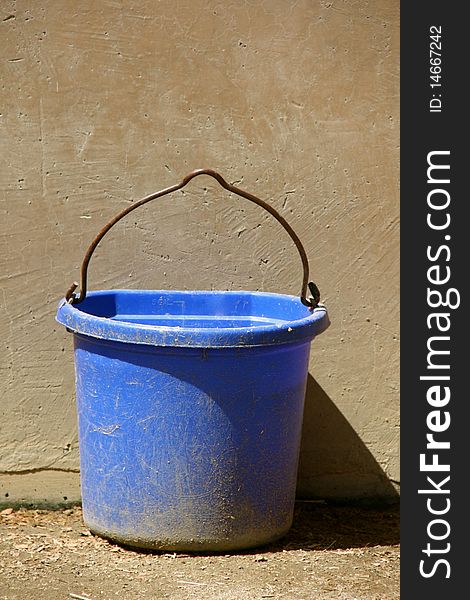 Blue bucket against a sandstone wall