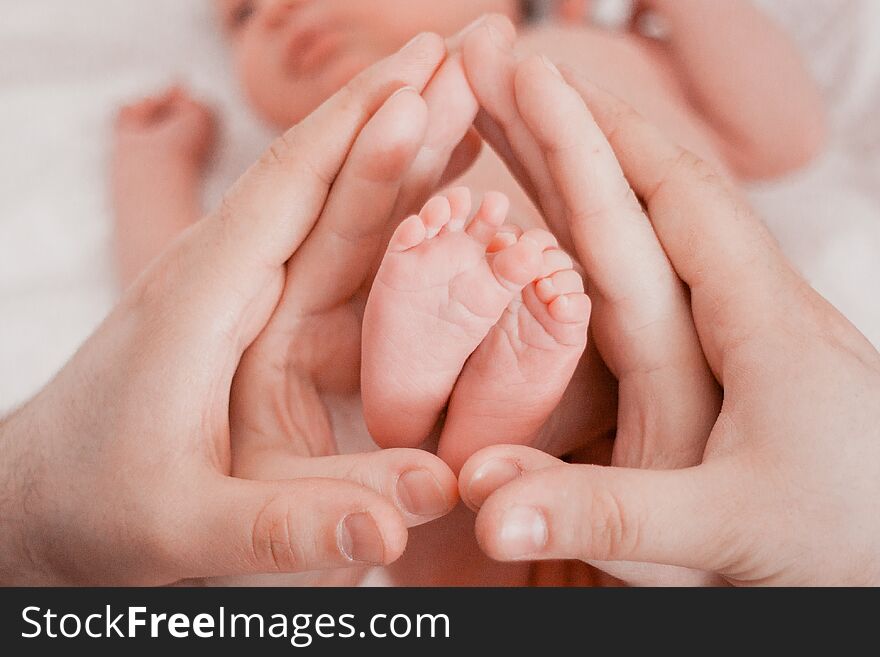 Pregnancy, maternity, preparation and expectation motherhood, giving birth concept. Newborn baby feet in hands of parents