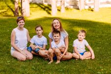 Happy Women And Children Sit On The Green Grass And Look At The Camera. Big Happy Family, Two Mothers And Three Children In White Royalty Free Stock Photography
