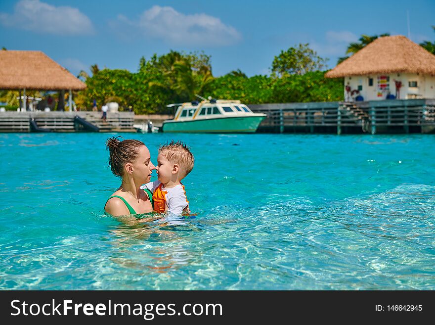 Three year old toddler boy on beach eskimo kissing his mother. Summer family vacation at Maldives. Three year old toddler boy on beach eskimo kissing his mother. Summer family vacation at Maldives