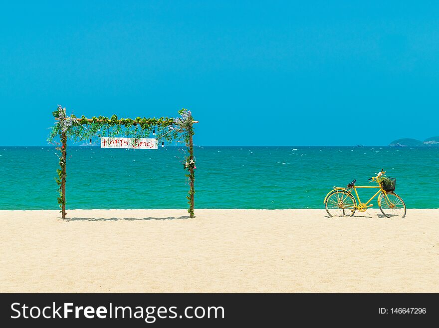 Wooden gate with flowers and old yellow bicycle on beach