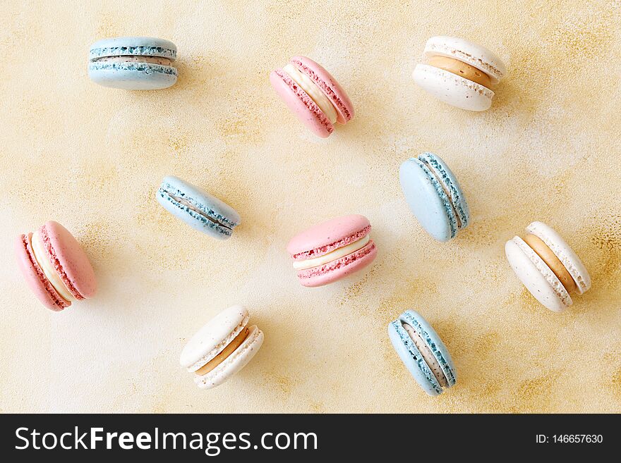 Minimalistic composition with bunch of french macaron sweets of different color and taste scattered over yellow grunged concrete texture background. Top view, close up, flat lay, copy space. Minimalistic composition with bunch of french macaron sweets of different color and taste scattered over yellow grunged concrete texture background. Top view, close up, flat lay, copy space