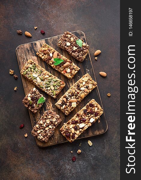 Various granola bars on dark rustic background, top view. Homemade healthy snack - granola superfood bars