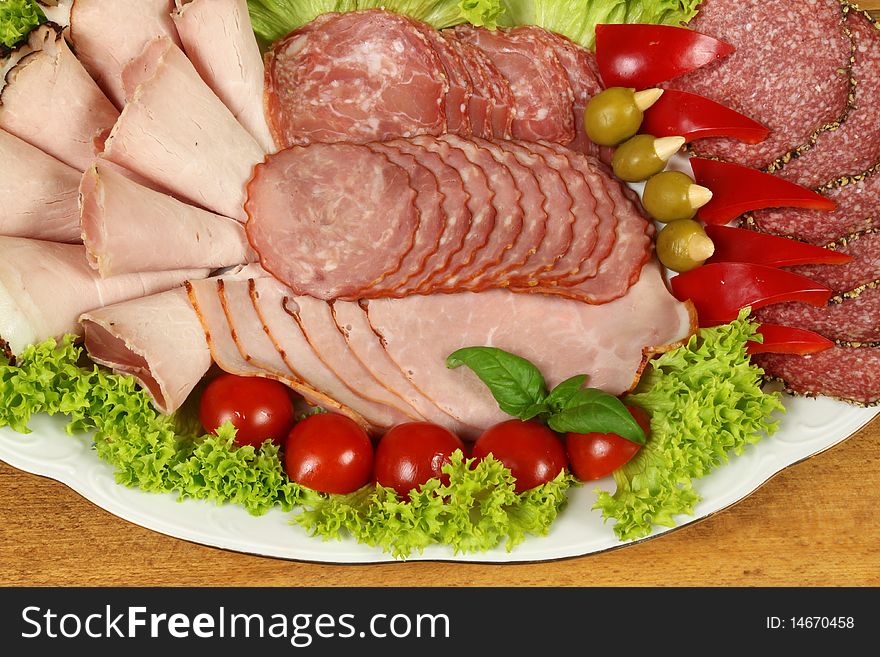 Banquet plate with slices of ham and sausage with garnish vegetables