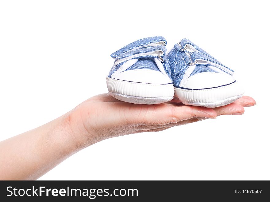 Female hand holds small baby shoes, studio shoot isolated on white background. Female hand holds small baby shoes, studio shoot isolated on white background