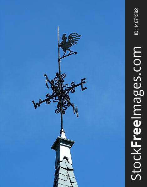 Rooster weather vane against blue sky