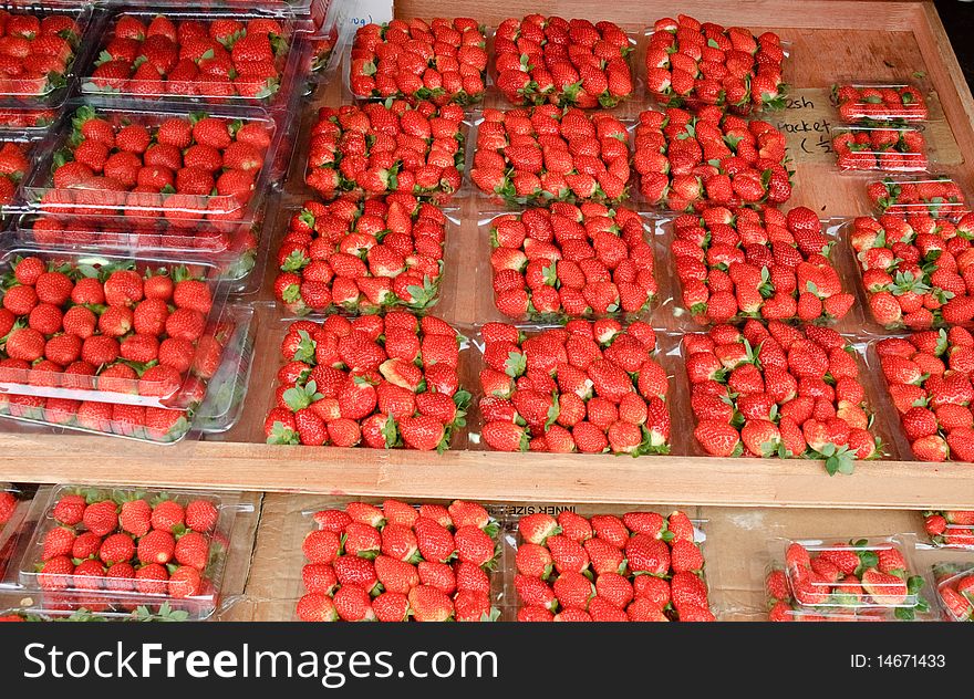 Bright red strawberries for sale at market with red background