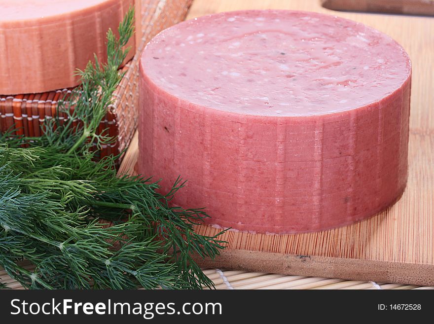 Sausage of the round form with small slices of fat on a kitchen board.