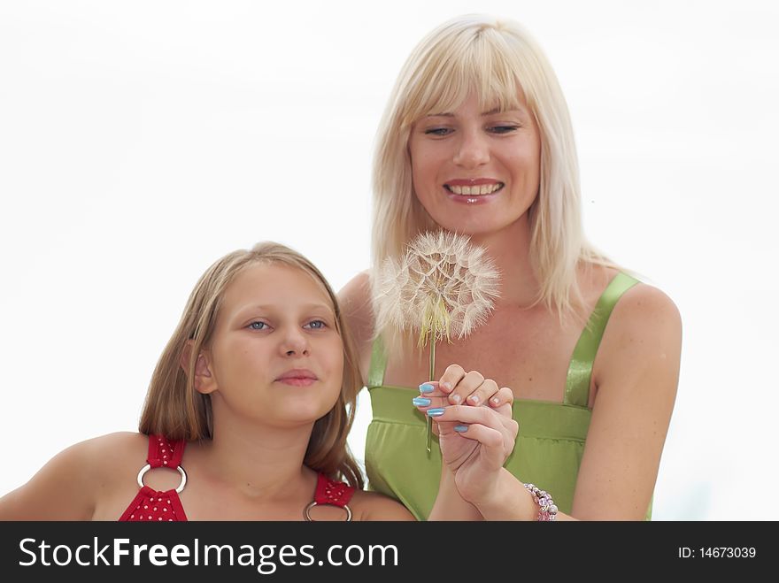 Mum with the girl blow on a dandelion on a light background. Mum with the girl blow on a dandelion on a light background