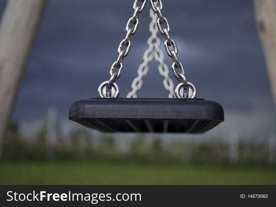 Low key image of a children's swing at a playground on a gloomy fall afternoon.