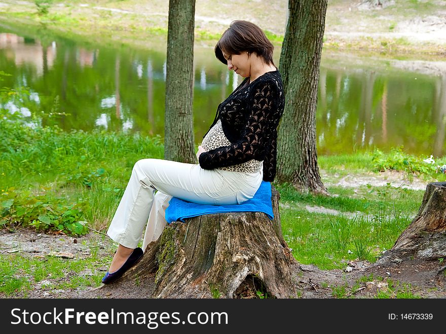 Beautiful pregnant girl in the park near lake.