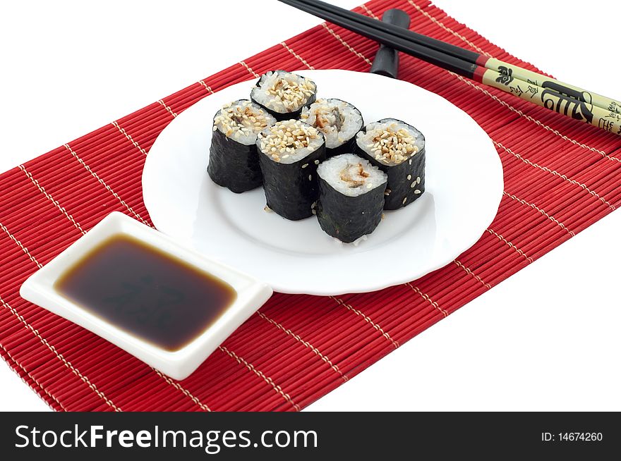 The Sushi, the chopsticks, soya sauce on a red bamboo mat on a white background. The Sushi, the chopsticks, soya sauce on a red bamboo mat on a white background