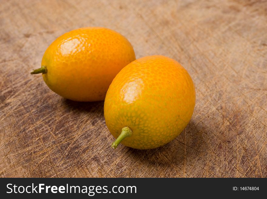 Two Kumquats On Old Table.