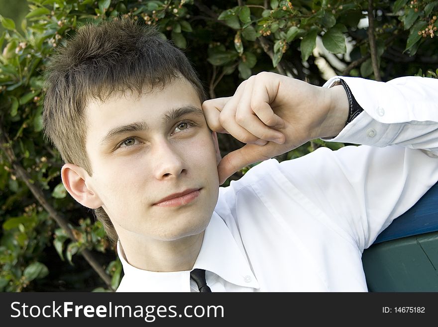 Guy in the park sits on a bench, propping up head on his hand, thinking. Guy in the park sits on a bench, propping up head on his hand, thinking