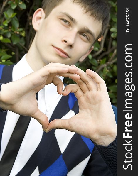 Teen boy in the park making heart shape with hands declaration of love