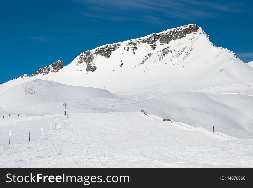 A view of alpine ski slope with a hight peak. A view of alpine ski slope with a hight peak.