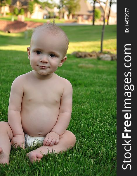 Smiling baby boy sitting in grass. Smiling baby boy sitting in grass