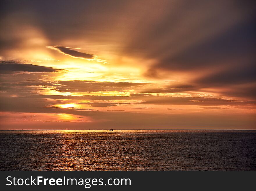 Scene of sunrise and beautiful sky background. Silhouette of a fisherman on longtail boat in the sea