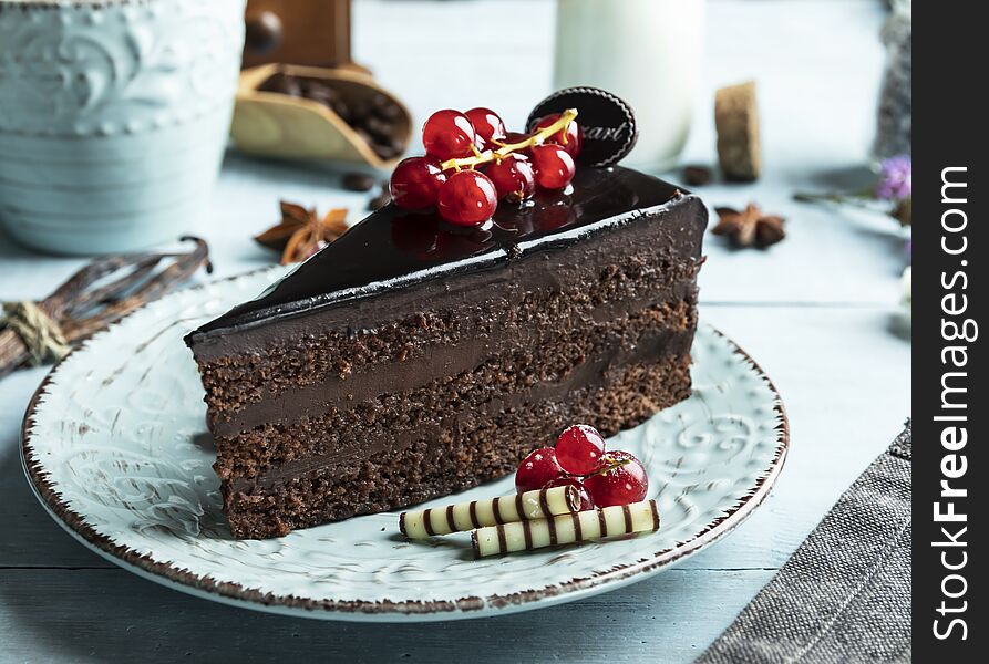 Dark chocolate cake mozart , red currant on the table a cup of coffee, cream.