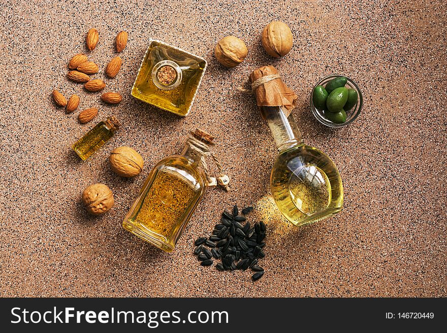 Flat lay a set of different oil in bottles, almond, walnut, sunflower and olive, brown background. View from above.