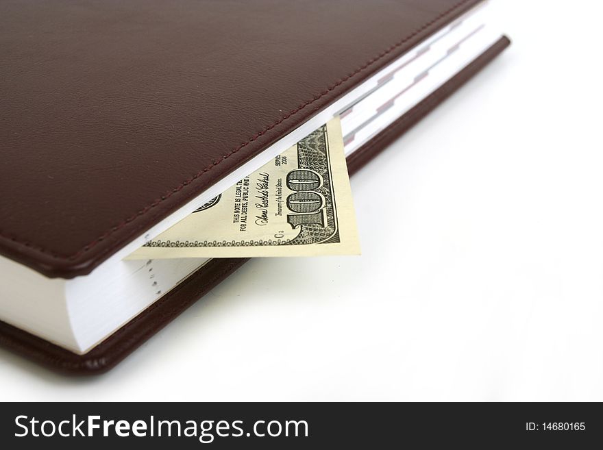 100 dollar bill in  brown notebook on white background