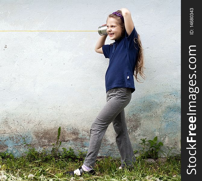 An image of a girl  with a toy-telephone outdoors. An image of a girl  with a toy-telephone outdoors